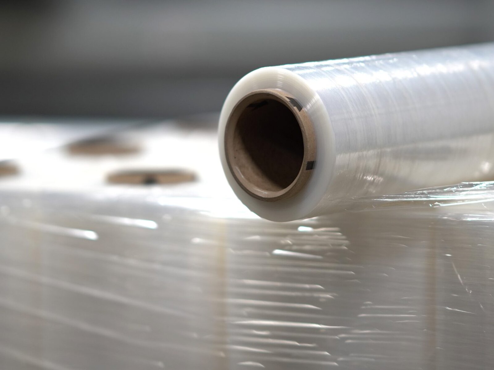 Close-up of a clear stretch film roll on a wrapped pallet inside an industrial warehouse